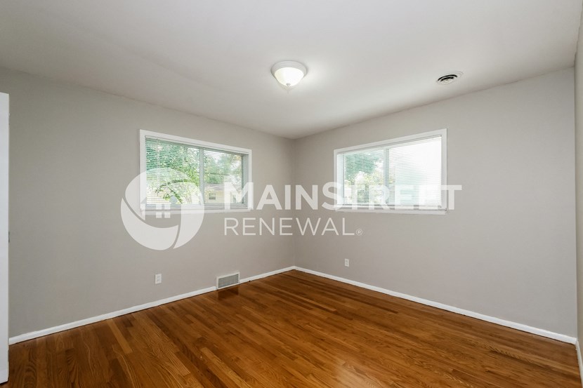 a bedroom with a hard wood floor and a window