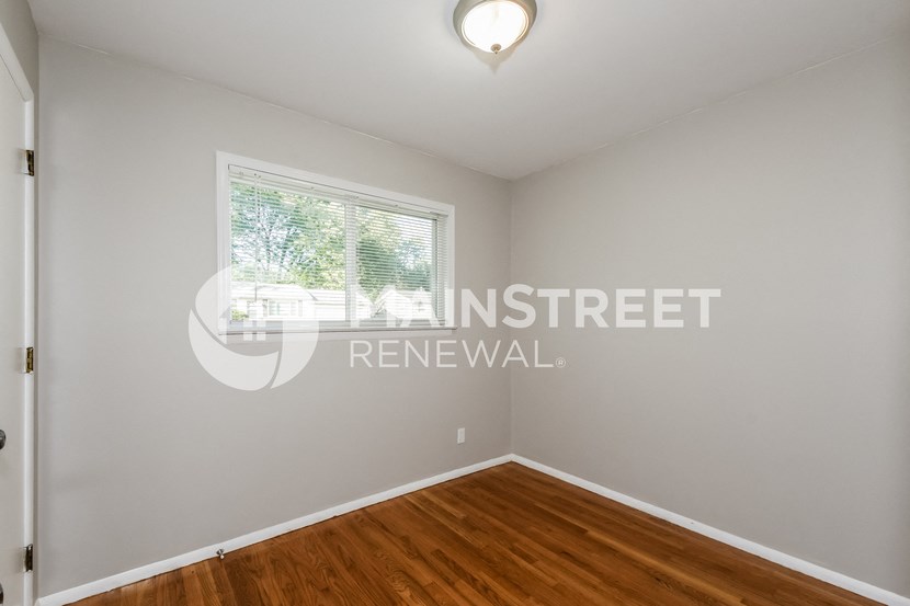 a bedroom with a hardwood floor and a window