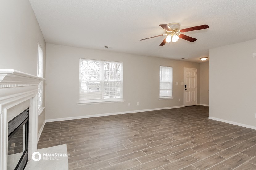 a living room with a fireplace and a ceiling fan