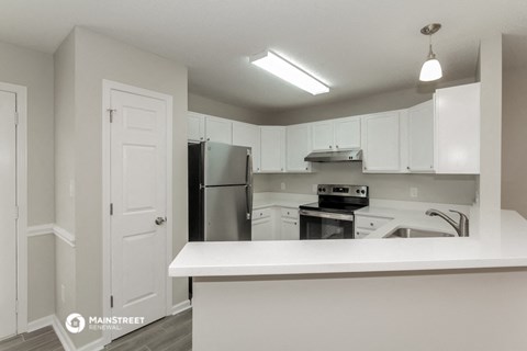 a white kitchen with white cabinets and a black refrigerator