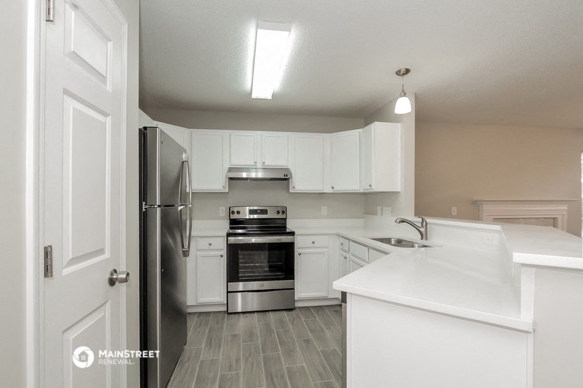 an empty kitchen with white cabinets and stainless steel appliances