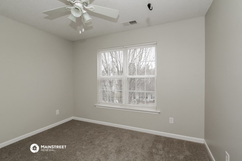 a bedroom with a large window and a ceiling fan