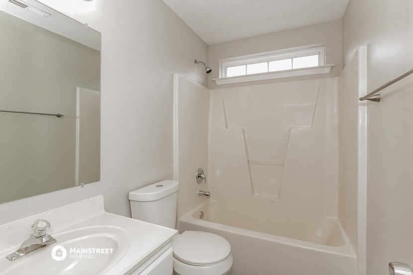 a bathroom with a toilet sink and tub and a mirror