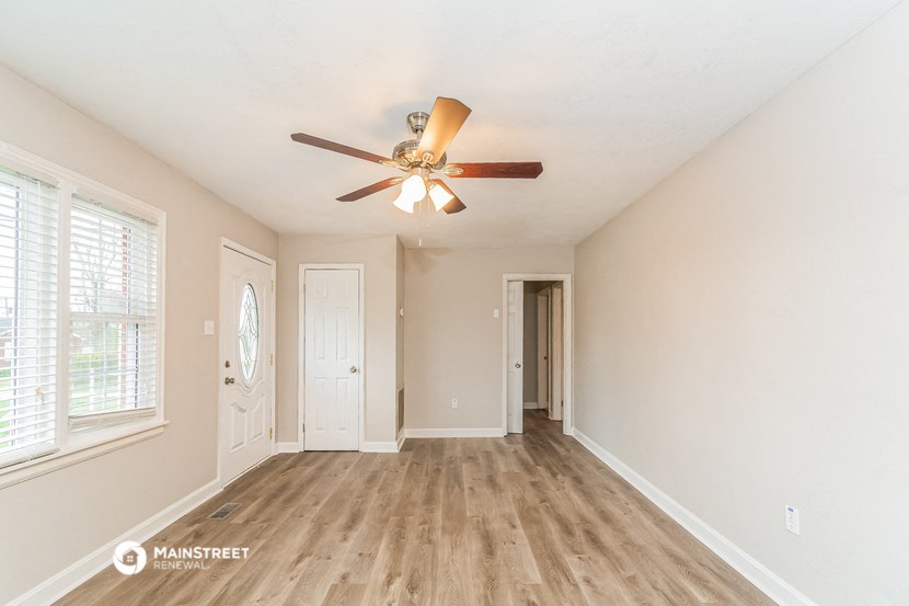 an empty living room with a ceiling fan