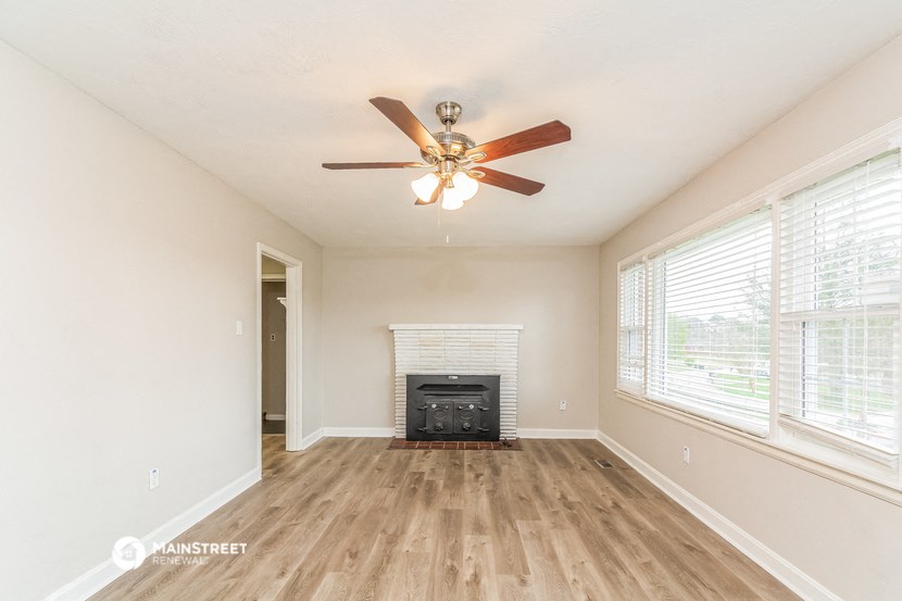 an empty living room with a ceiling fan and a fireplace