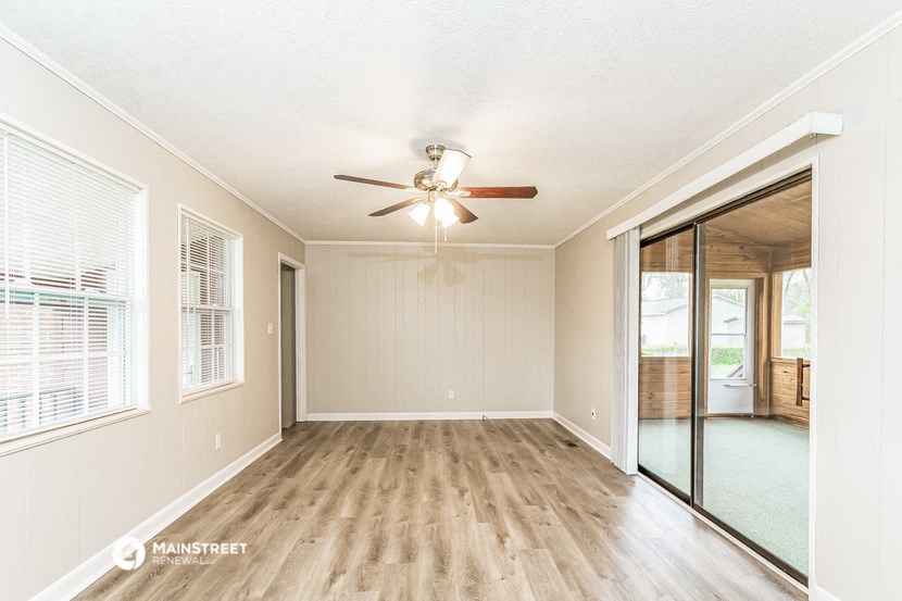 an empty living room with a ceiling fan and a sliding glass door