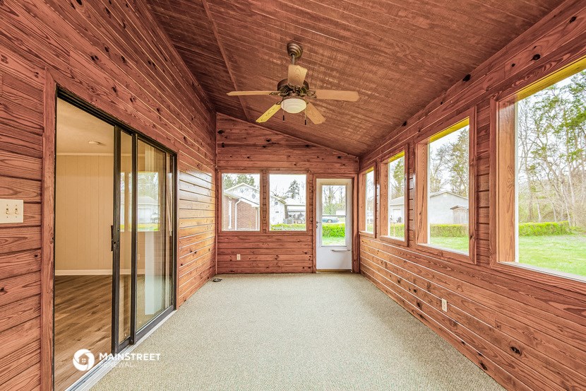 a covered porch with a ceiling fan and glass doors