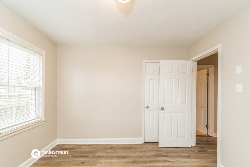 a bedroom with a door and a closet and a window