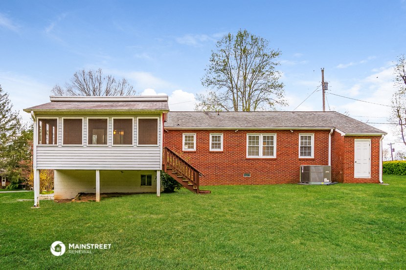 a red brick house with a white porch and a lawn