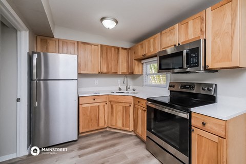 a kitchen with wood cabinets and black appliances and a stainless steel refrigerator