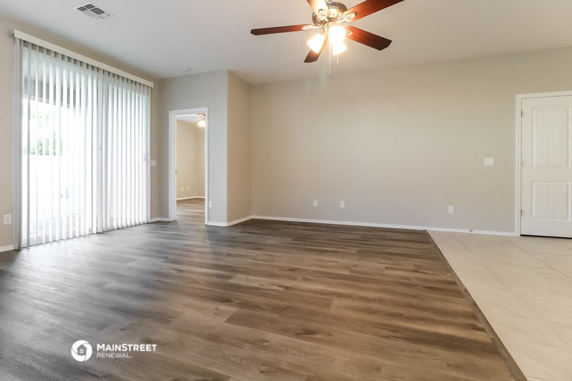 an empty living room with wood floors and a ceiling fan