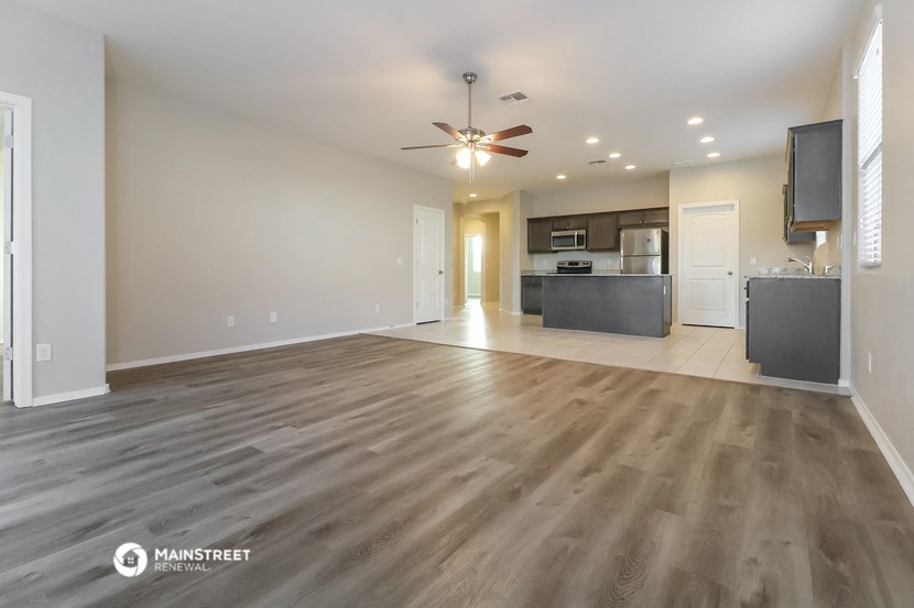 an empty living room and kitchen with a ceiling fan