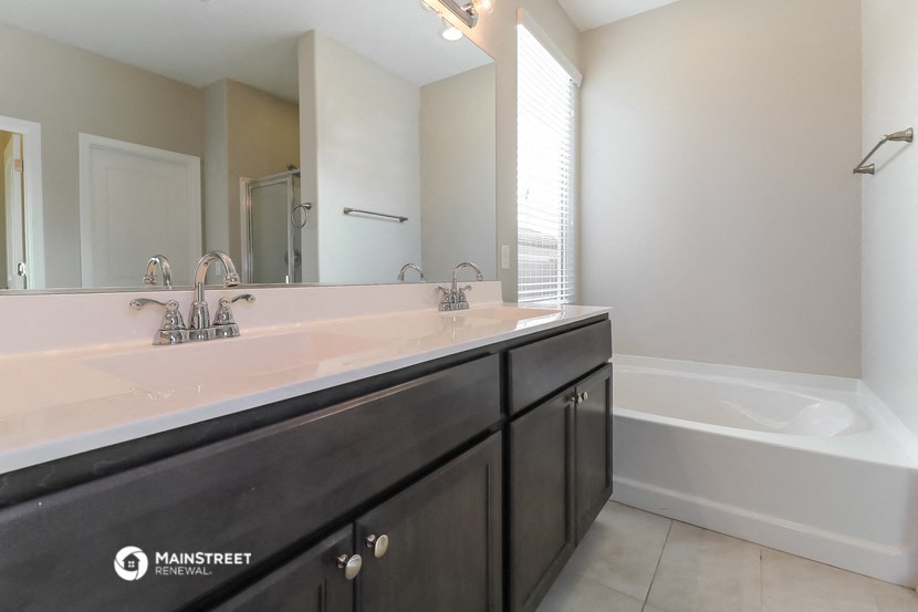 a bathroom with a sink and a tub and a large mirror