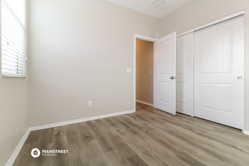a bedroom with white walls and wood flooring and white doors