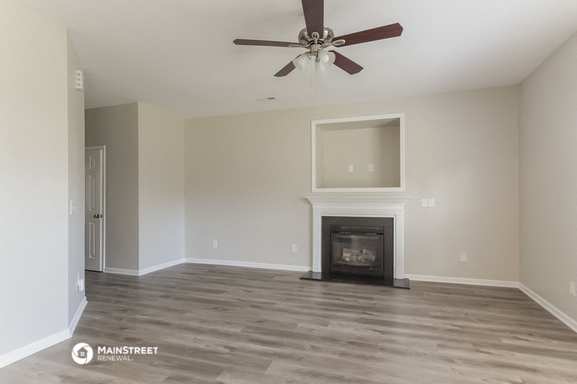 a living room with a fireplace and a ceiling fan