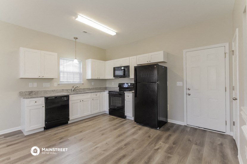 the kitchen of an apartment with black appliances and white cabinets