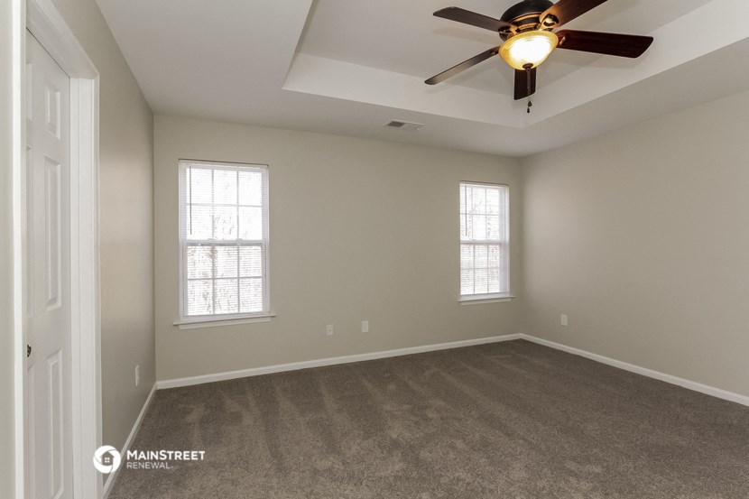 the spacious living room with carpet and a ceiling fan