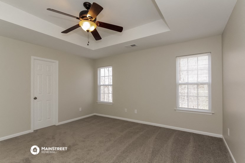 the spacious living room with ceiling fan and window