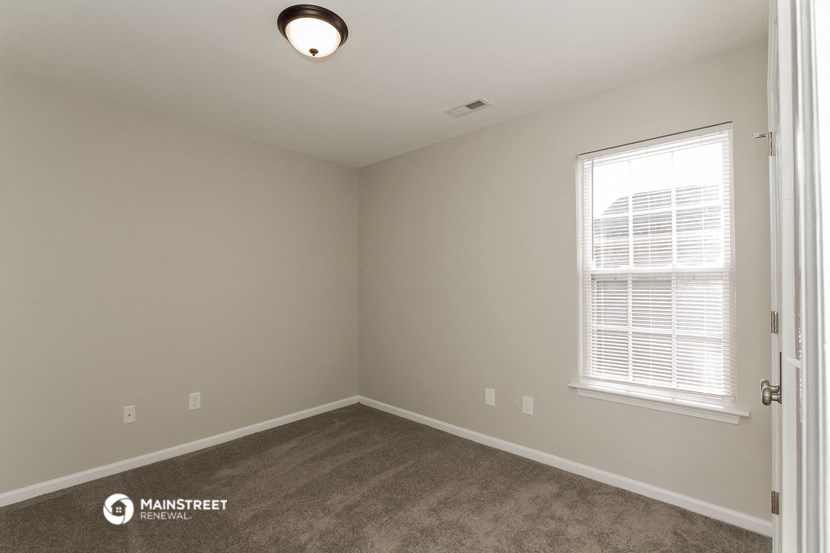the spacious living room with carpeting and a window