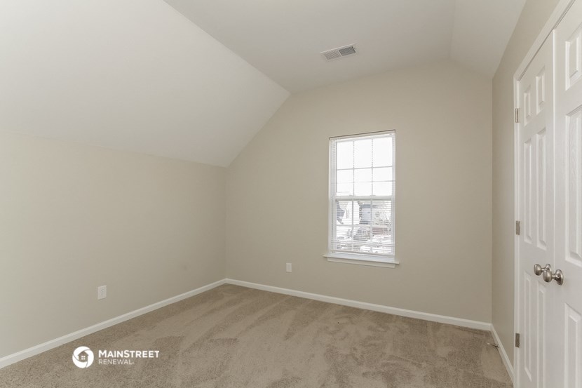a bedroom with carpet and a window and a door