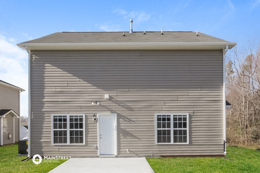 the front of a small gray house with a white door