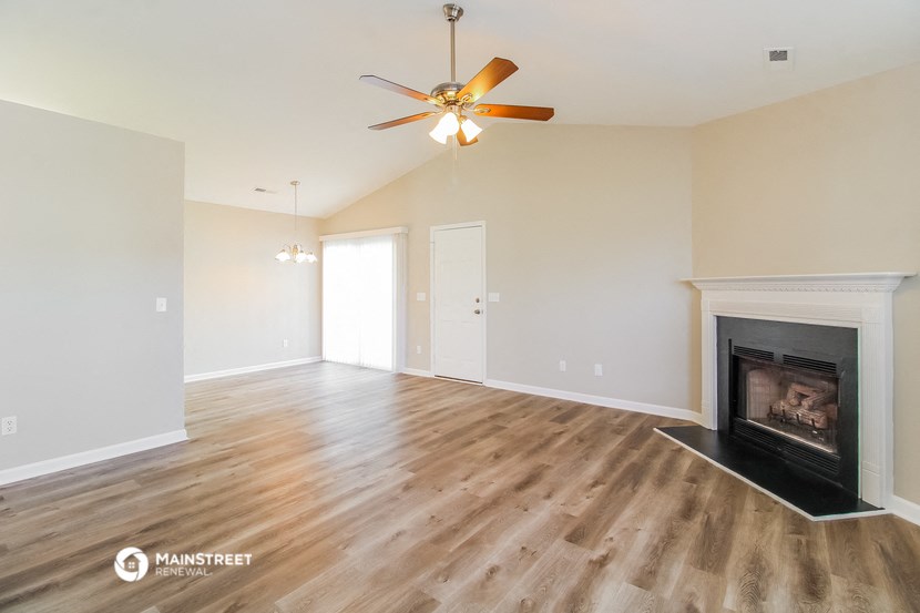 a living room with a fireplace and a ceiling fan