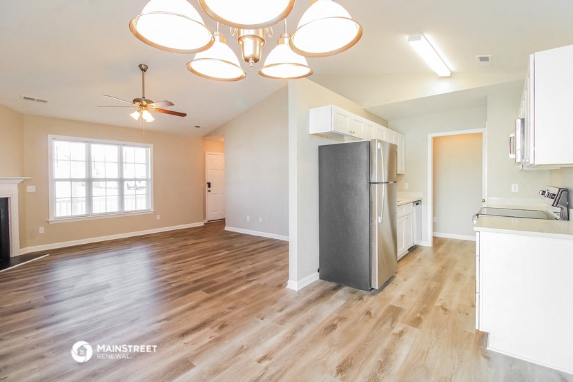 an empty kitchen and living room with a refrigerator