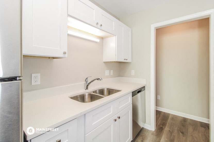 an empty kitchen with white cabinets and a sink