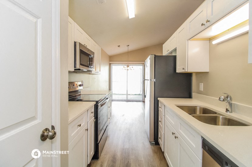 an empty kitchen with stainless steel appliances and white cabinets