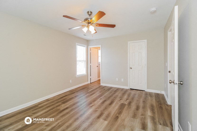 a living room with a ceiling fan and a door to a hallway