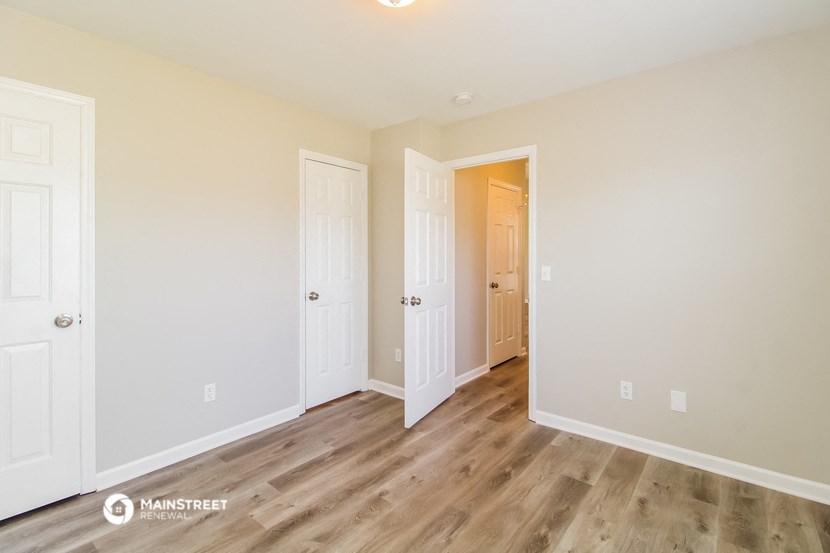 the living room of an apartment with wood floors and white walls