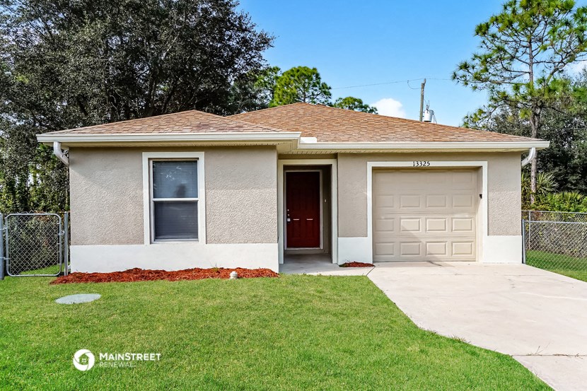 a small tan house with a garage and a lawn