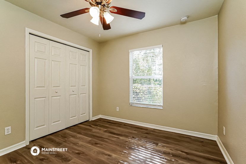 the bedroom of a house with a ceiling fan and a window