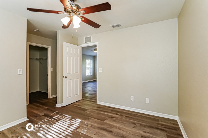 a living room with a ceiling fan and a door to a hallway
