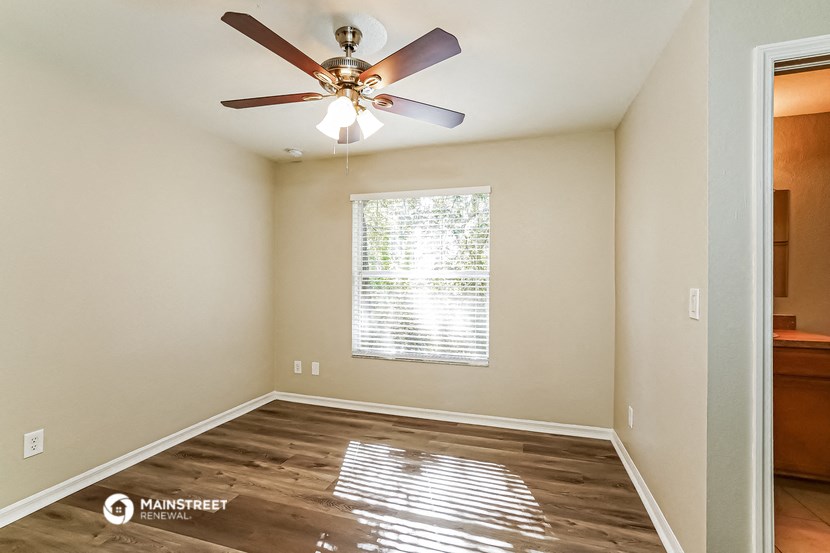 the bedroom has a large window and a ceiling fan