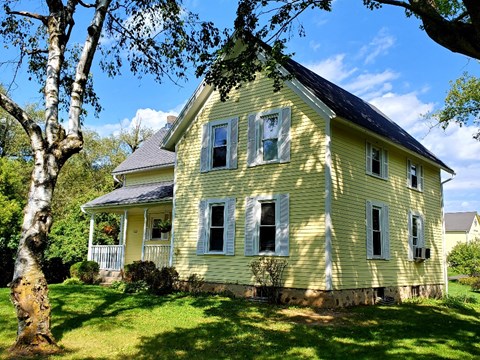 A yellow house with a tree in front.