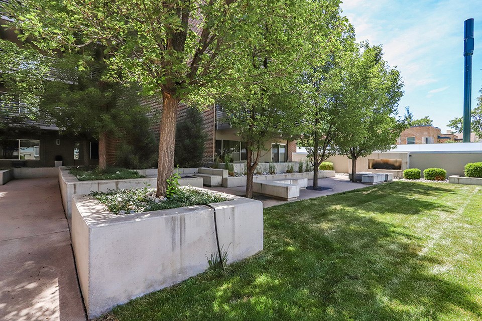 a courtyard with trees and benches in front of a building