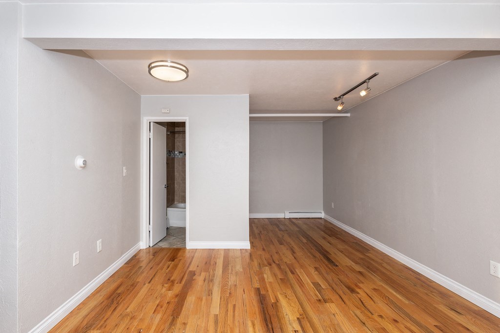 an empty living room with wood flooring and white walls