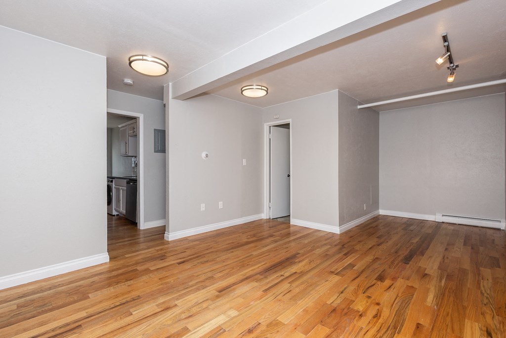 an empty living room with wood flooring and grey walls