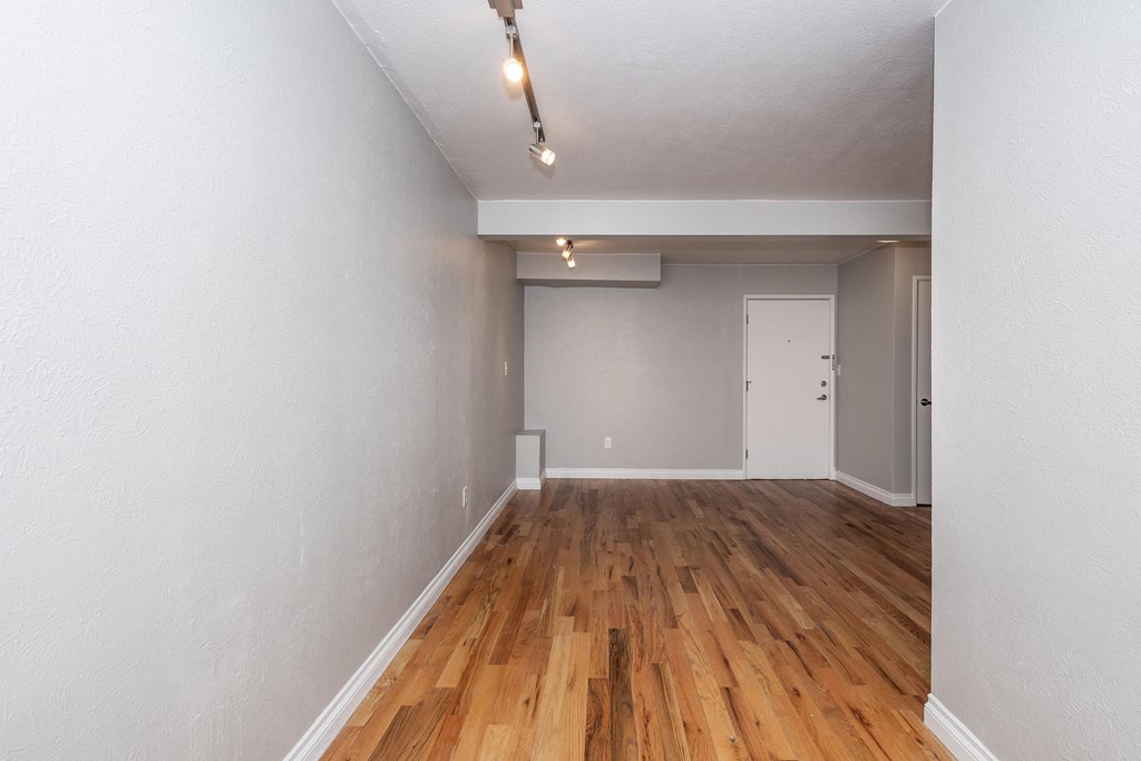 the living room and dining room of an apartment with wood floors and white walls