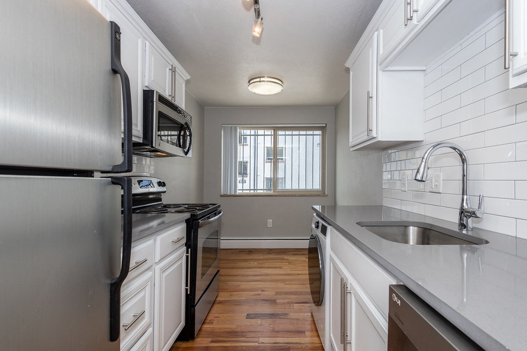 an empty kitchen with stainless steel appliances and white cabinets