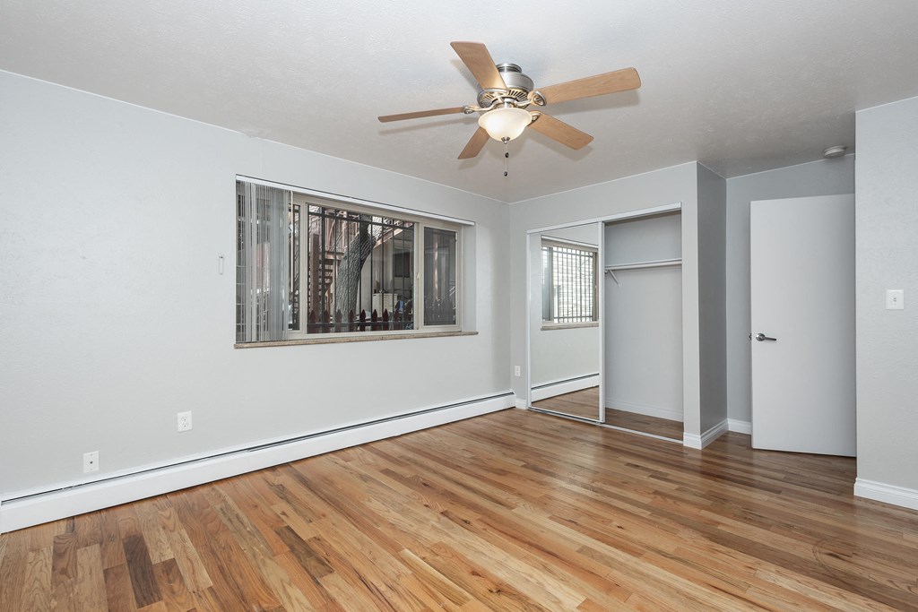 an empty living room with a ceiling fan and a window