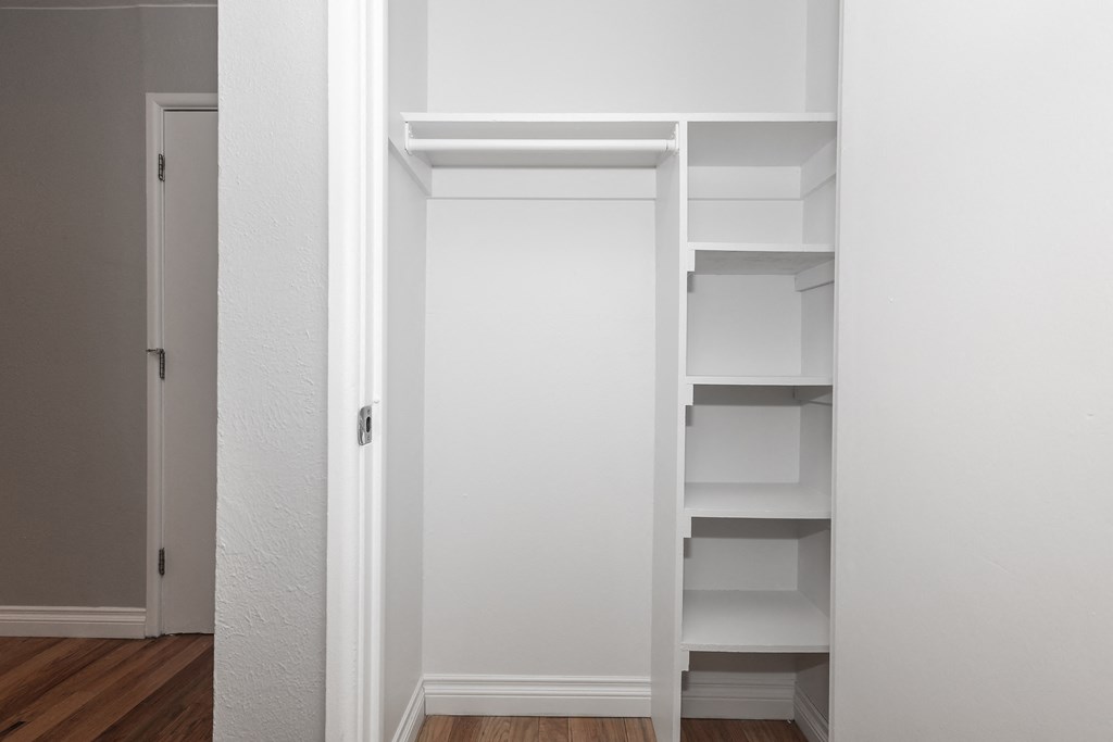 a closet with white shelves and a white door
