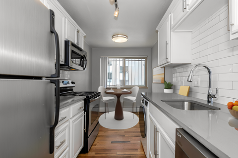 a kitchen with white cabinets and black appliances and a table