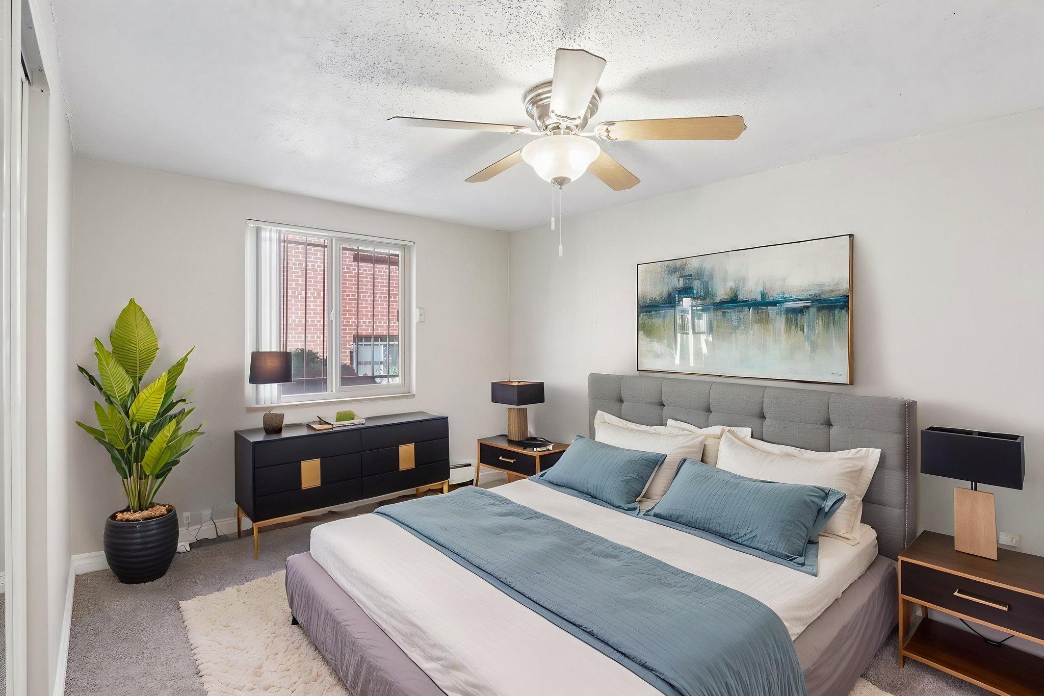 A bedroom with a bed, nightstands, and a plant.