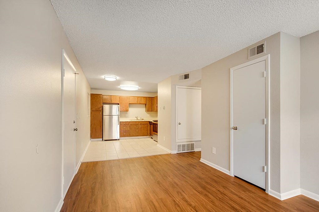 an empty living room and kitchen with a hard wood floor