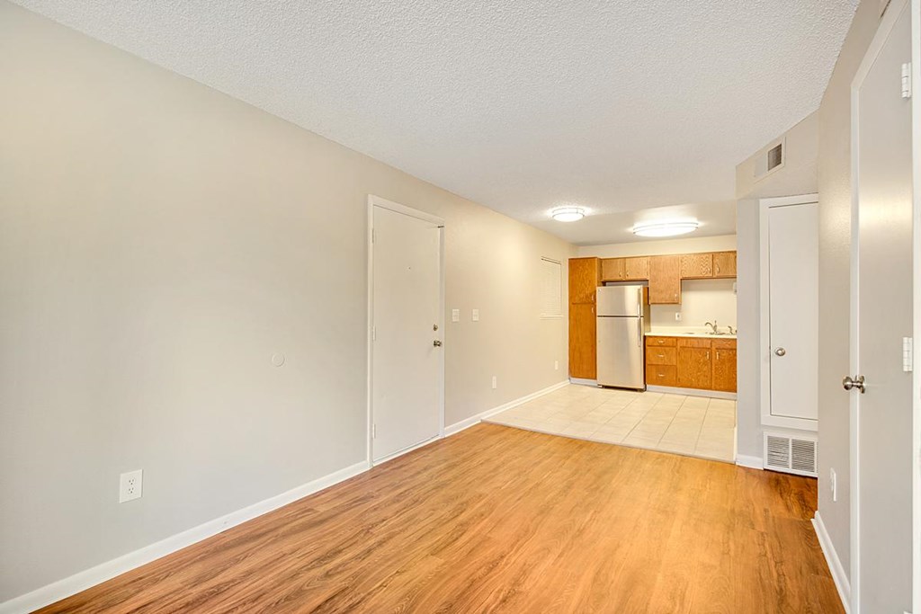 an empty living room and kitchen with wood flooring