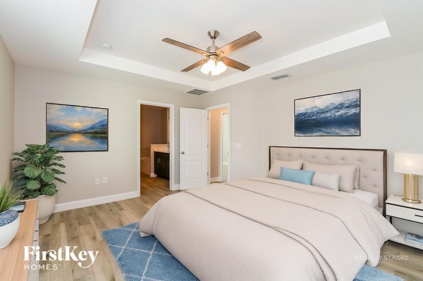 A bedroom with a large bed, a ceiling fan, and two pictures on the wall.