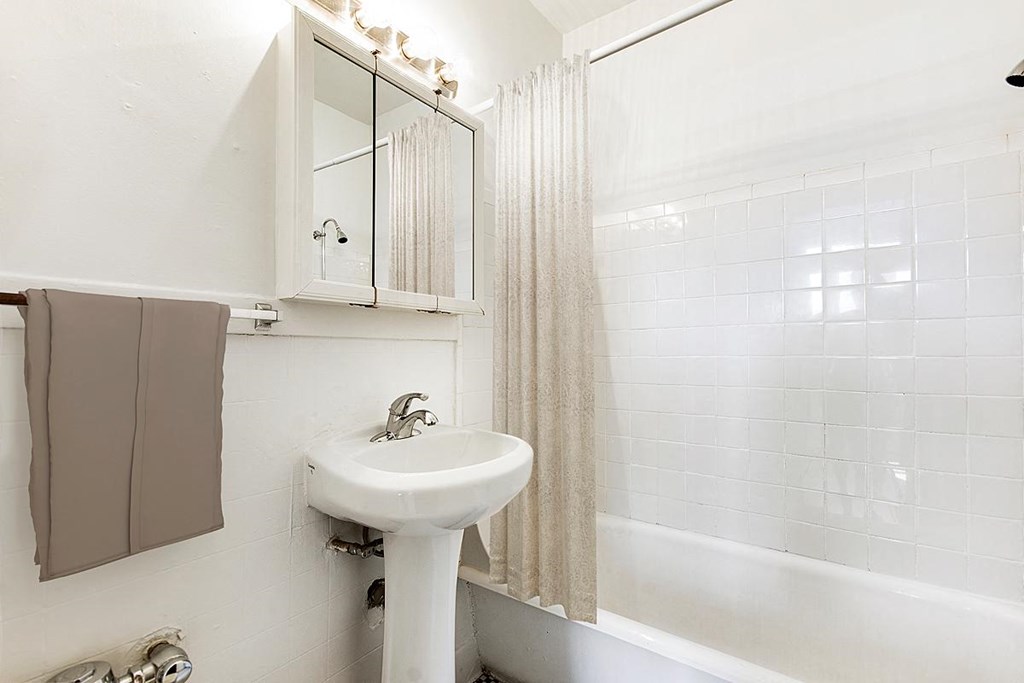 A white sink in a bathroom with a mirror above it.