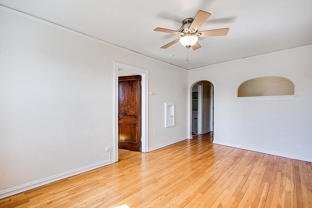 A room with a ceiling fan and wooden floors.